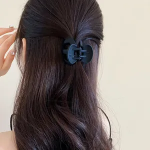 Close-up of a minimalist matte black wavy hair claw clip styled on dark brown hair in a half-updo