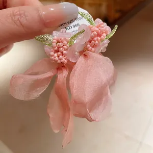 Vista dettagliata di orecchini a fiore rosa fatti a mano con garza e ago d'argento