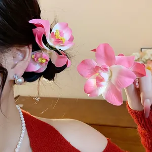 Vue détaillée des pinces à cheveux fleurs en tissu rose portées et tenues pour un style vacances.