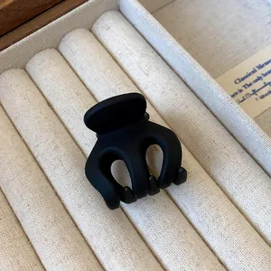 Detailed macro view of a matte black mini hair claw clip with a wavy design on fabric