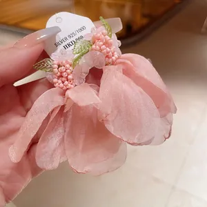 Vista dettagliata degli eleganti orecchini a fiore in tulle rosa con accenti di perle