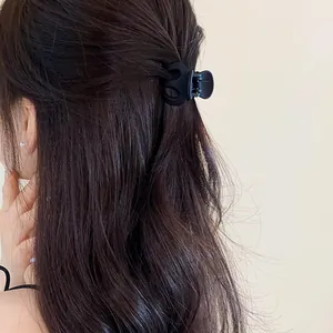 Detailed view of a matte black wave hair claw clip styled on brunette hair.