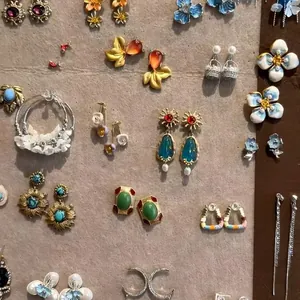 Collection of stylish floral and geometric beaded stud earrings displayed on a craft board