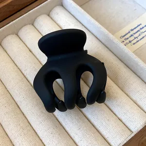 Detailed macro shot of a minimalist matte black wave hair claw clip in a velvet box