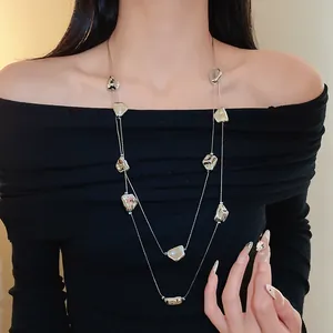 Détail d'un collier double couche argenté à motifs irréguliers porté par un mannequin