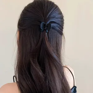 Back view of a matte black butterfly hair claw clip securing a half-up hairstyle