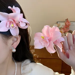 Vue détaillée d'une pince à cheveux fleurie en tissu rose faite main, portée et tenue en main.