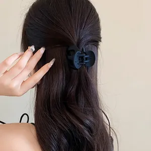 Close-up of a matte black wavy hair claw clip worn on wavy brown hair