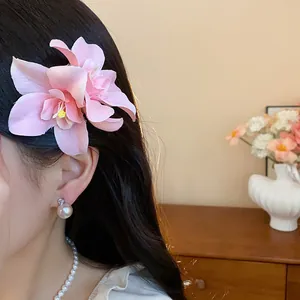 Gros plan d'une élégante pince à cheveux en fleur de tissu rose portée par un mannequin.