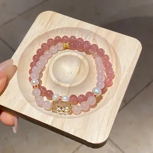 Close-up of strawberry and rose quartz beaded bracelets with gold bow charm and pearls