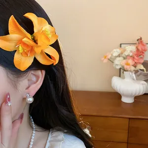 Vue détaillée d'une pince à cheveux fleur en tissu orange portée sur les cheveux d'une femme.