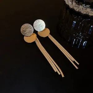 Gold-tone tassel earrings featuring textured circular plates and delicate metal chains.
