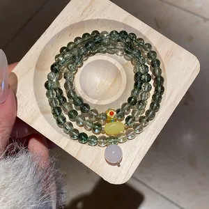 Macro view of green crystal multi-layer bracelet with gold flower and yellow gemstone