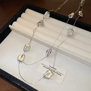 Gros plan sur les perles argentées irrégulières d'un collier long à double épaisseur