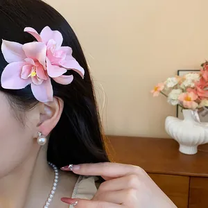 Vue détaillée d'une élégante pince à cheveux en fleur d'orchidée en tissu rose portée.