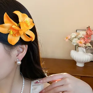 Gros plan d'une pince à cheveux réaliste en fleur de tissu orange portée par un mannequin