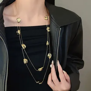Gros plan d'un collier double épaisseur doré plissé sur une veste en cuir noir