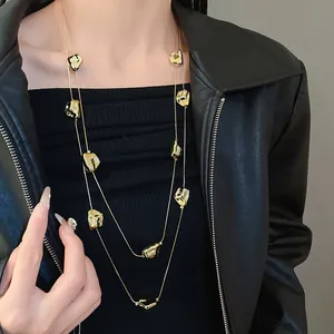 Gros plan d'un collier long à deux couches avec breloques dorées irrégulières sur un modèle.