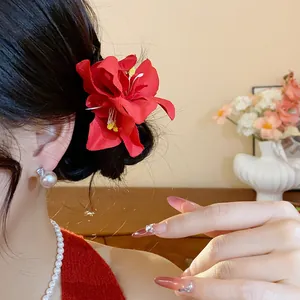 Vue détaillée d'une pince à cheveux fleur en tissu rouge vif sur un chignon de modèle élégant