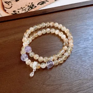 Detailed view of citrine beaded bracelet with silver flower charms and pendant