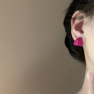 Close-up detail of magenta minimalist triangle stud earrings worn on a female ear