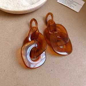 Macro detail of amber-colored acrylic geometric chain link earrings with warm tones.