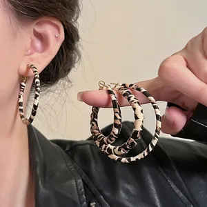 Macro detail of retro leopard print resin hoop earrings with a stylish textured finish