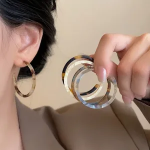 Detail of vintage resin hoop earrings featuring leopard and marble textures on model