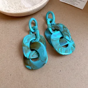 Detail view of chunky acrylic geometric link earrings with blue marble texture.