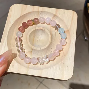 Detail of a natural crystal beaded bracelet with a butterfly charm on wood.