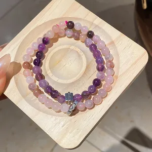 Close-up of double-layered purple and pink natural stone beaded bracelets on wooden tray