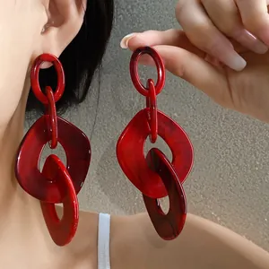 Detailed close-up of chunky red acrylic geometric earrings worn on ear