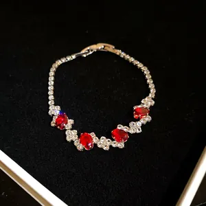 Close-up of a silver-tone bracelet featuring brilliant red oval stones and clear zircons