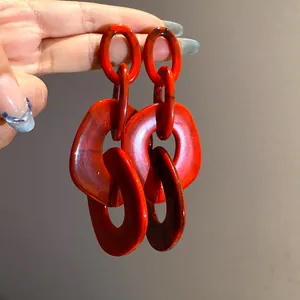 Detailed macro view of large red acrylic geometric chain link earrings with marble texture