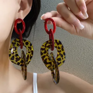 Detailed close-up of exaggerated leopard print acrylic drop earrings worn by an Asian model.