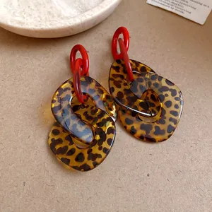 Close-up detail showing the leopard print pattern and red chain links of acrylic earrings