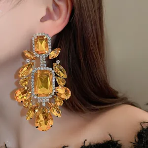 Close-up of statement vintage earrings featuring large amber square and teardrop crystals.
