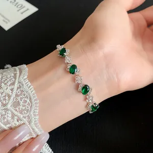Detailed close-up of emerald green zircon bracelet on wrist with elegant lace sleeve detail