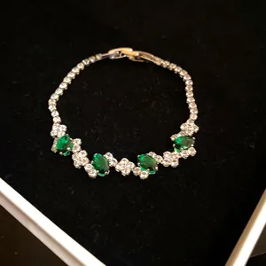 Detailed macro shot of an elegant irregular bracelet featuring green oval zirconia gemstones