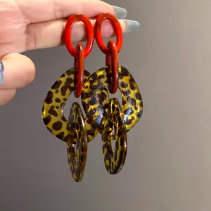 Close-up view of chunky leopard print acrylic earrings featuring vibrant red oval links.