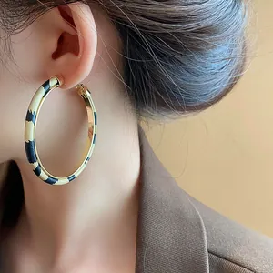Detailed close-up of retro leopard print resin hoop earrings worn by a model.