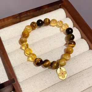 Elegant handmade tiger's eye and yellow crystal bead bracelet featuring a gold floral charm