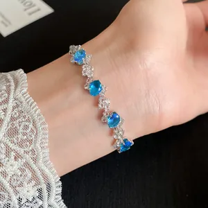 Detailed view of an irregular zircon bracelet featuring sparkling oval blue stones on a wrist