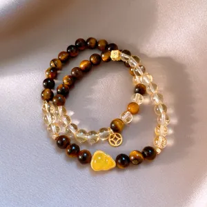 Close-up of tiger's eye and yellow crystal bracelets with gold gourd and coin charms