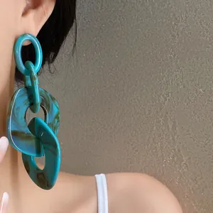 Detailed view of oversized acrylic geometric chain earrings with teal marble texture
