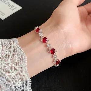 Elegant silver-toned bracelet featuring oval red zircons, shown on a wrist with lace.