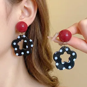 Stylish retro black and white polka dot hollow flower earrings featuring red stud accents.