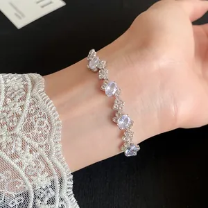 Detail view of an irregular oval zircon bracelet worn on a wrist with lace cuff.
