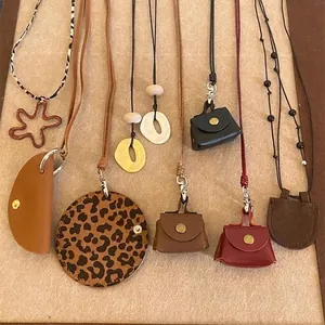 Close-up of various leather bag geometric pendant necklaces on a beige display surface