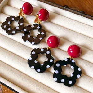 Macro view of retro earrings with red ball studs and black polka dot flower pendants